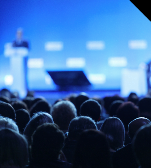 Público em evento com palco ao fundo